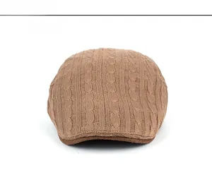 Detailed close-up showing the brown knit pattern and cable stitch texture of the flat cap