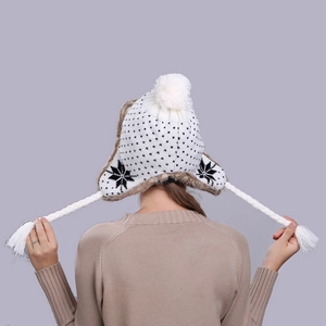Winter white knitted trapper hat with snowflake patterns, plush faux fur lining and tassels