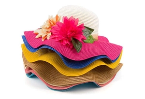 Detail view of colorful stacked sun hats with large floral accents and wavy brim design