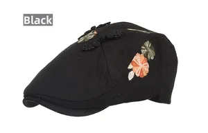 Detail of black newsboy cap featuring elegant floral embroidery and chic bow buckle decor