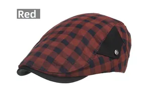 Détail de la casquette plate à carreaux rouge et noir avec empiècement et logo en métal