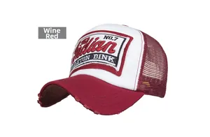 Detail of vintage wine red trucker hat with embroidered patch and distressed brim texture