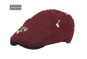 Detail of wine red newsboy cap with floral embroidery and traditional button