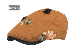 Detailed view of ginger yellow newsboy hat with intricate floral embroidery on textured fabric