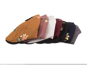 Detail showing various colors of newsboy caps with floral embroidery on white background
