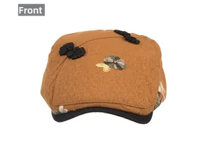 Detailed front view of a vintage beige newsboy cap with floral embroidery and satin bow