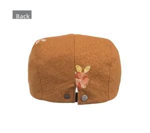 Back view of brown newsboy cap with floral embroidery and adjustable snap buttons