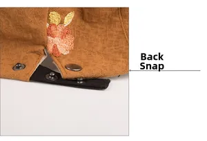 Detailed close-up of vintage floral embroidery and metal back buckle on textured newsboy cap