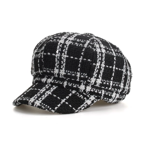 Close-up of black and white checkered newsboy cap with textured tweed fabric detail