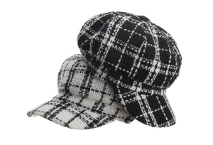 Close-up of black and white tweed newsboy caps with textured weave and short brim detail