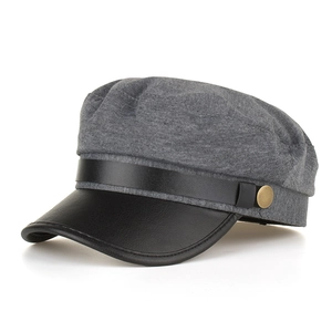 Macro detail of newsboy cap showing grey wool texture, black leather brim and gold buckle
