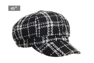 Detail view of black and white houndstooth tweed newsboy cap showing woven fabric texture