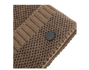 Détail macro du tissu en maille marron avec un bouton décoratif noir mat et bordure côtelée