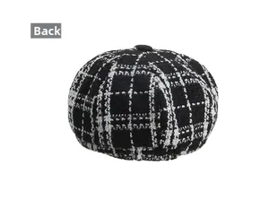 Macro detail of the back view of a black and white plaid tweed beret hat with button