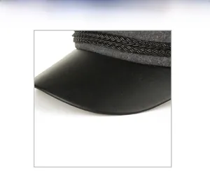 Detail view of newsboy cap featuring black PU leather brim and grey wool texture