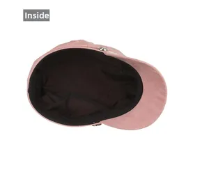 Internal view of pink faux suede newsboy cap showing black lining and metal button detail