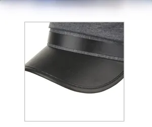 Detail of grey wool blend beret with black leather strap and fine stitching finish