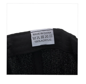 Detail shot of the internal care label on a black acrylic baseball cap showing 100% material