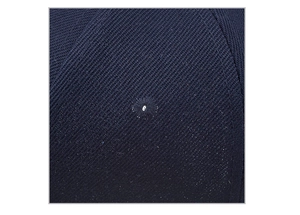 Dettaglio macro del cappello blu navy che mostra il tessuto twill e i fori di ventilazione