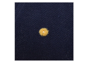 Detailed macro view of yellow circular embroidery on dark blue twill baseball cap fabric