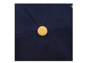 Close-up of baseball cap top button and navy blue twill fabric with contrast stitching