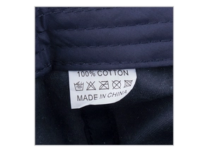 Macro shot of 100% cotton washed fabric inner care label on navy blue baseball cap