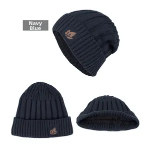 Detail view of navy blue cable knit beanie featuring warm fleece lining and leaf patch