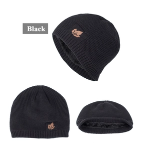 Detail of black knitted beanie with warm fleece lining and brown maple leaf patch