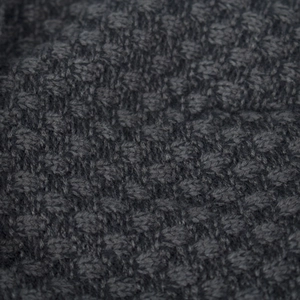 Macro view of dark grey waffle knit fabric texture on a short cuff beanie hat
