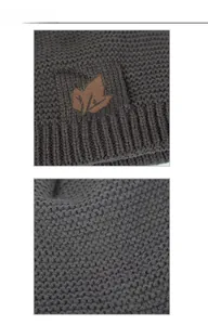 Detail view of dark grey knitted winter beanie with brown maple leaf leather patch and ribbed edge
