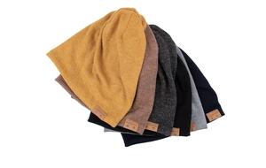 Detail der Stricktextur und des Lederetiketts an mehrfarbigen Beanie-Mützen