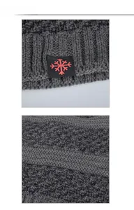 Macro shot of dark grey chunky knit fabric with a red snowflake label on the beanie