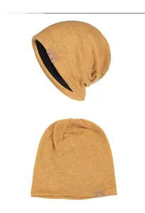Detailansicht der gelben Strickmütze mit Lederetikett und schwarzem Innenfutter