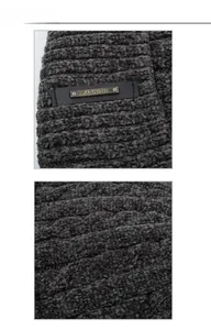 Detail of grey chenille cable knit fabric with a leather Fashion logo metal plate