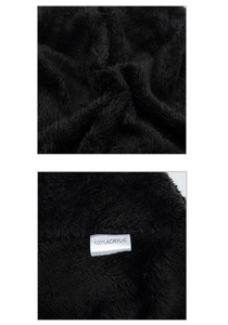 Close-up of black 100% acrylic faux fur material showing soft fluffy texture and tag