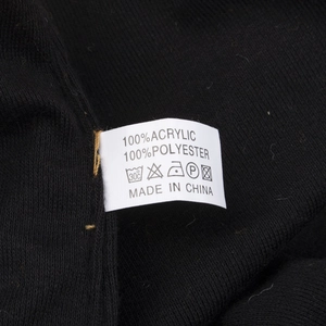 Detailansicht des Etiketts der schwarzen Strickmütze aus Acryl und Polyestergewebe