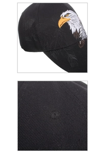 Detailed close-up of bird embroidery and textured cotton fabric on a black baseball cap
