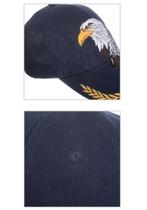 Dettaglio ricamo aquila e foglie di alloro dorate su un cappellino in cotone blu scuro