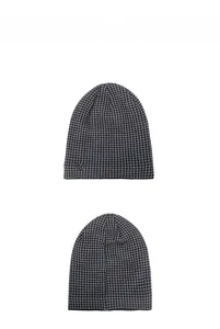 Detailed close-up of knit beanie with black and white houndstooth pattern and metal logo