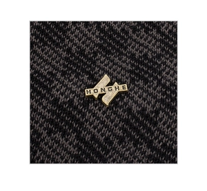 Vue macro d'une étiquette métallique en bronze sur un bonnet en tricot gris foncé