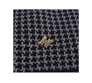Macro view of houndstooth knit fabric with a bronze metal logo plate on the front