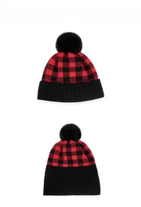 Close-up of red and black checkered knit beanie with a black faux fur pompom detail