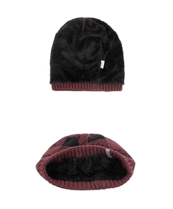 Detail view of burgundy knitted beanie with thick black faux fur lining and fabric label