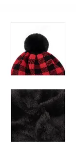 Detail of red and black buffalo plaid knitted winter hat with fleece lining and pompom