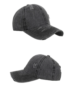 Detail view of washed distressed baseball cap with vintage ripped holes and dark gray texture