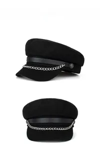 Detail view of black newsboy cap featuring silver chain trim and anchor button accents
