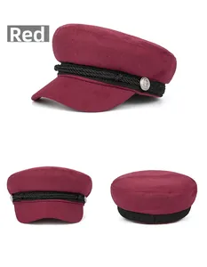 Detail of red wool newsboy cap with black braided cord and silver anchor buttons