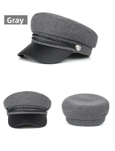 Detail view of grey wool newsboy cap with black leather brim and metal buttons