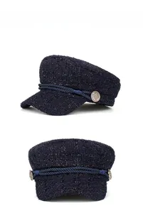 Detail of dark blue tweed newsboy cap with metallic embossed buttons and rope trim