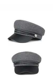 Detail of grey wool newsboy cap with black leather brim and silver button accents